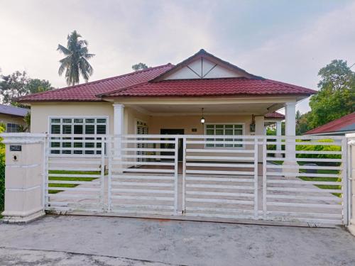 a house with a white fence in front of it at Homestay Moslim Kampung Bentong in Kluang