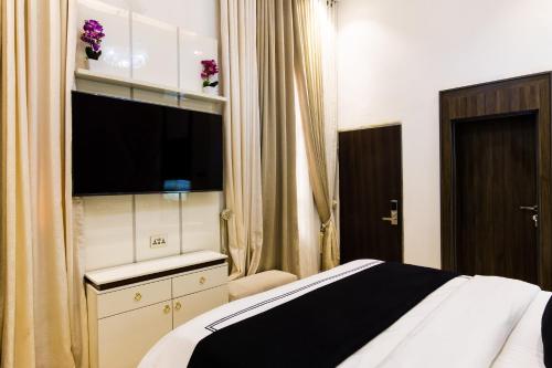 a hotel room with a bed and a flat screen tv at Yellow Trumpet Residence Asokoro in Asokoro