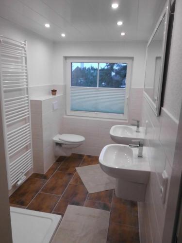 a bathroom with two sinks and a toilet and a window at Kleines-Landhaus-Kopendorf in Bojendorf