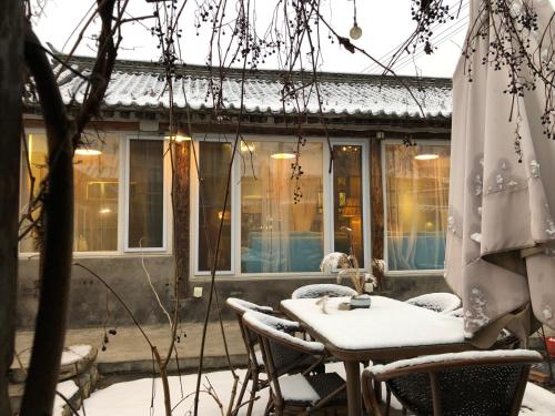 a table and chairs in the snow on a patio at 北京怀柔福喜山慕田峪长城特色民宿 in Beizhai