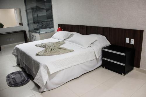 a bedroom with a large white bed with a wooden headboard at Vera Cruz Business Hotel in Acailandia