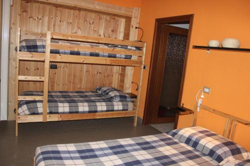 a bedroom with two bunk beds and an orange wall at La Madonnina in Villa di Tirano