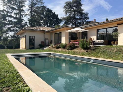 une piscine devant une maison dans l'établissement Superbe maison 234 m² avec piscine chauffée, à Saint-Didier-au-Mont-dʼOr