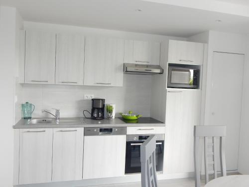 une cuisine blanche avec un évier et un micro-ondes dans l'établissement ST Malo Bel appartement prés gare plage du sillon parking privé, à Saint-Malo