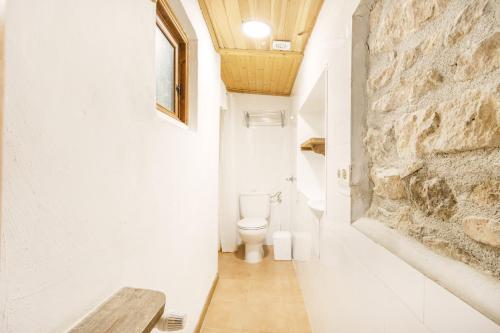 a bathroom with a toilet and a stone wall at La Caseta De Sant Grau in Navés