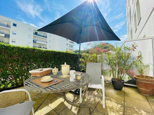 une table et des chaises avec un parasol sur une terrasse dans l'établissement Casa Coeur Maine, à Angers