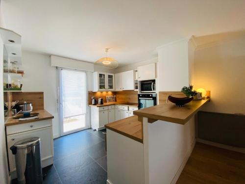 une cuisine avec des armoires blanches et un comptoir en bois dans l'établissement Casa Coeur Maine, à Angers