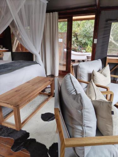 a bedroom with a bed and a couch and chairs at Barefoot Addo Elephant Lodge in Addo