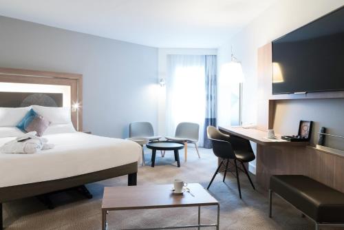 ベルサイユにあるノボテル シャトー ドゥ ヴェルサイユのベッドとデスクが備わるホテルルームです。