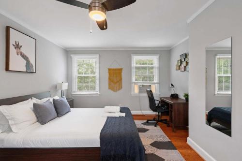 a bedroom with a bed with a desk and windows at Charming Townhouse Retreat by CozySuites in Alexandria
