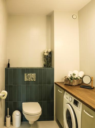 a bathroom with a toilet and a washer and dryer at Retro Night - Apartment - Jezioro Malta in Poznań