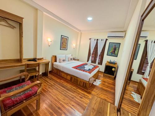 a bedroom with a bed and a desk in a room at Luang Phasouk Hotel in Luang Prabang