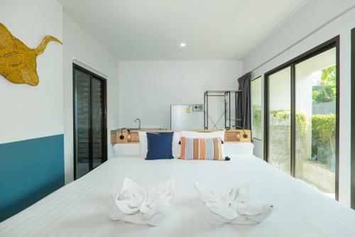 a bedroom with a large white bed with two white chairs at KRAAM Silhouette Hotel and Cafe Phuket in Chalong 