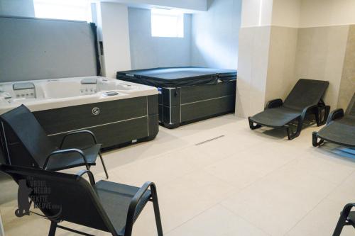 a room with a bed and chairs and a tub at Vila Ursul Negru in Sovata