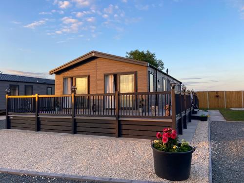 a tiny house with a fence and a flower pot at Bluebell Lodge at The Peaceful Cherry Lea Holiday Park and Fishing Lake Skegness in Skegness
