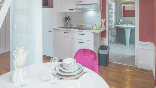 cocina blanca con mesa y silla rosa en BonAppart 14 - Charme Napoléonien & Confort, en Troyes