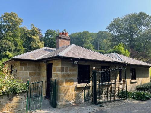 an old stone house with a black gate at Marnwood Lodge in Coalbrookdale