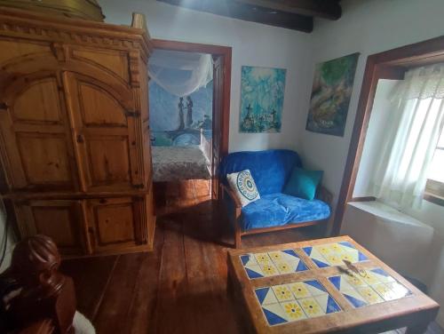 a living room with a blue couch and a bedroom at Rivendell Eco lodge in El Paso