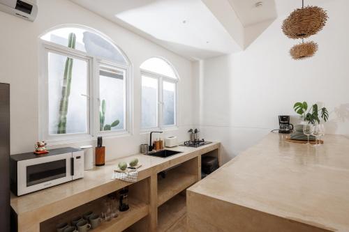 a kitchen with a counter with a microwave and two windows at Jacuzzi 3BR - Echo beach - walking distance in Canggu