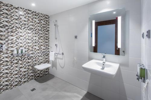 a white bathroom with a sink and a shower at Hampton By Hilton Gdansk Oliwa in Gdańsk