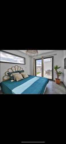 - une chambre avec un grand lit bleu et une fenêtre dans l'établissement Maison individuelle, à Combaillaux