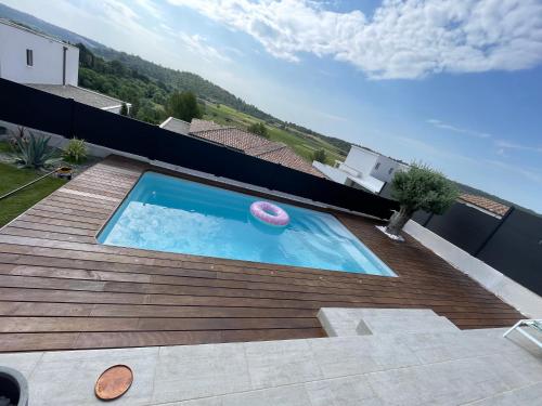une piscine avec un frisbee sur une terrasse en bois dans l'établissement Maison individuelle, à Combaillaux