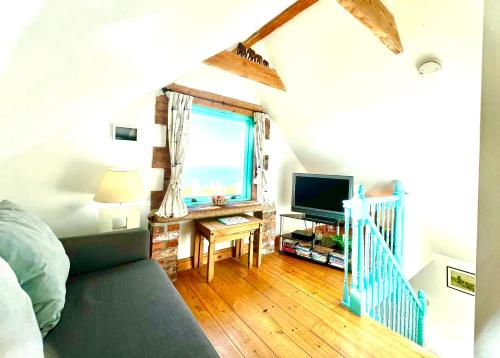 a bedroom with a couch and a television in a room at DRIFTWOOD - Super 1 Bedroom Home with Sea Views in Saint Levan