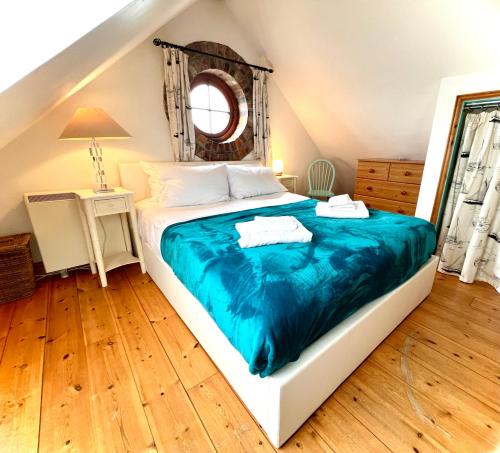 a bedroom with a large bed with a blue blanket at DRIFTWOOD - Super 1 Bedroom Home with Sea Views in Saint Levan