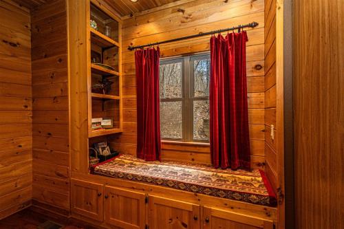 a log cabin room with a window and red curtains at Millstone Lodge in Bryson City