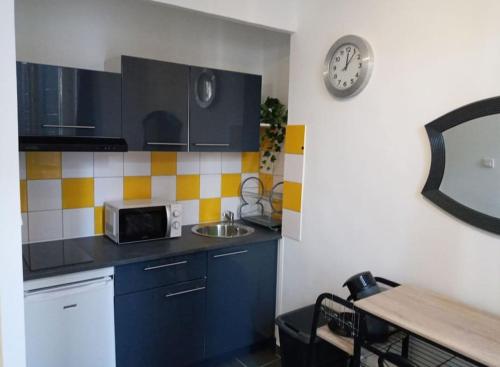 une cuisine avec un évier et une horloge murale dans l'établissement Proche gare,centre,vieux-port, à Marseille