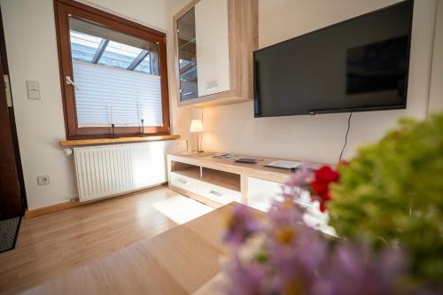 a living room with a television and a table with flowers at Haus unterm Mammutbaum - Elberadweg in Magdeburg