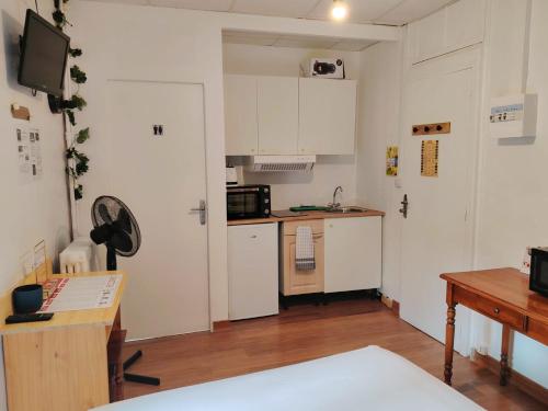 une petite cuisine avec des armoires blanches et une table dans l'établissement Studio N2 Appartement Hôtel Combes, à Amélie-les-Bains-Palalda