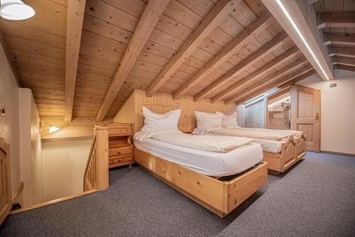 two beds in a room with wooden ceilings at Appartamenti Anna in Livigno