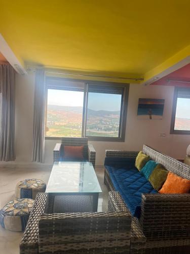 a living room with couches and a table and windows at LOFT Avec une vue paradisiaque in Imouzzer Kandar