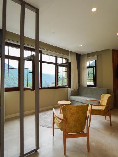 a living room with a couch and chairs and windows at Ayder Altıparmak Suit in Ayder Yaylasi