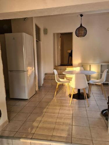 une cuisine avec une table, des chaises et un réfrigérateur dans l'établissement Confortable maison à la campagne, à Les Fougères