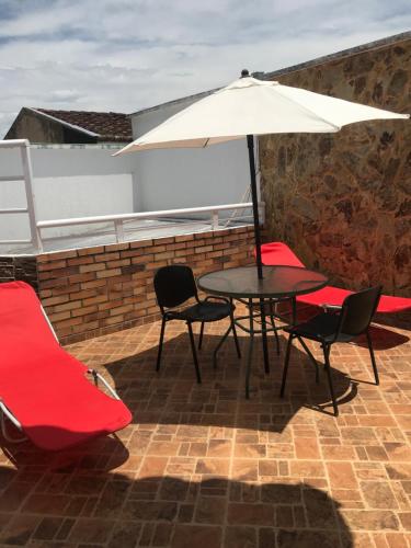 a table and chairs with an umbrella on a patio at Linda casa con jacuzzi in Roldanillo