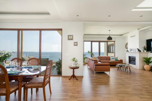a living room with a table and chairs and a couch at Beachfront Villa Atalandia with Heated Pool, Gym, BBQ & Office in Goúdhouros