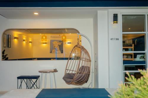 a swinging chair in a room with a table at KRAAM Silhouette Hotel and Cafe Phuket in Chalong 