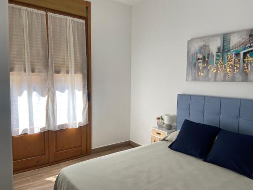a bedroom with a bed with a blue headboard and a window at C-MAyOR 2 personas in Alcalá de Henares