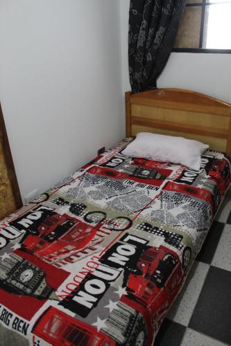 a bed with a comforter on it in a room at Hostel Mirador Aukán in Bogotá