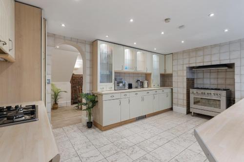 a large kitchen with white cabinets and appliances at Parea Living - Spacious 4 Story House, Families, Big Groups in London
