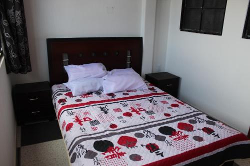 a bedroom with a bed with a red and white quilt at Hostel Mirador Aukán in Bogotá