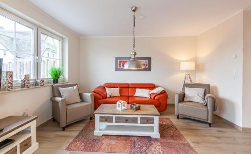 a living room with an orange couch and two chairs at Seeteufel in Zingst