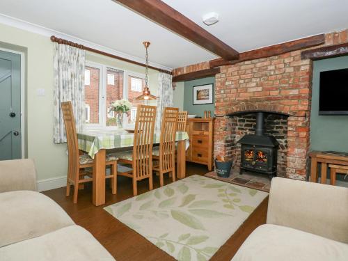 a living room with a table and a fireplace at Easter Cottage in Dersingham