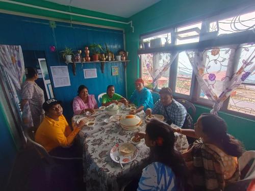 a group of people sitting around a table eating at White Sea Homestay in Kurseong