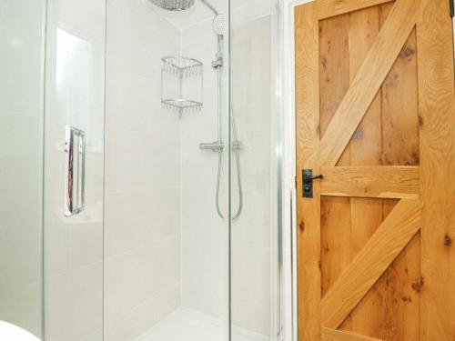 bagno con doccia e porta in legno di Easter Cottage a Dersingham