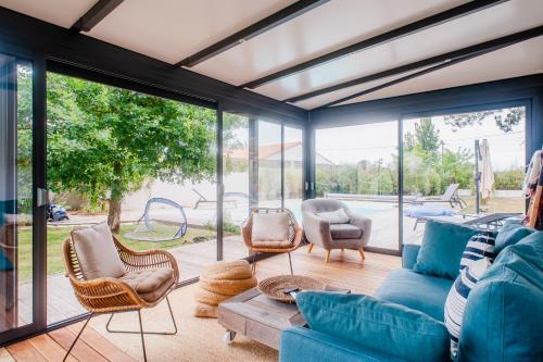 ein Wohnzimmer mit einem blauen Sofa und Stühlen in der Unterkunft "LA VILLA DES HAUTES MER" Villa 4 étoiles, 10 personnes, piscine privée chauffée, parc arboré, proche plage et marais in Talmont