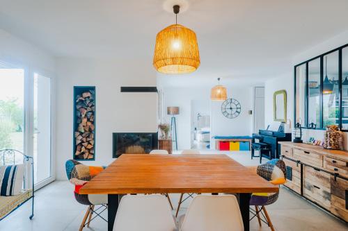ein Esszimmer mit einem Holztisch und Stühlen in der Unterkunft "LA VILLA DES HAUTES MER" Villa 4 étoiles, 10 personnes, piscine privée chauffée, parc arboré, proche plage et marais in Talmont