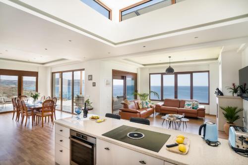 a kitchen and living room with a view of the ocean at Beachfront Villa Atalandia with Heated Pool, Gym, BBQ & Office in Goúdhouros